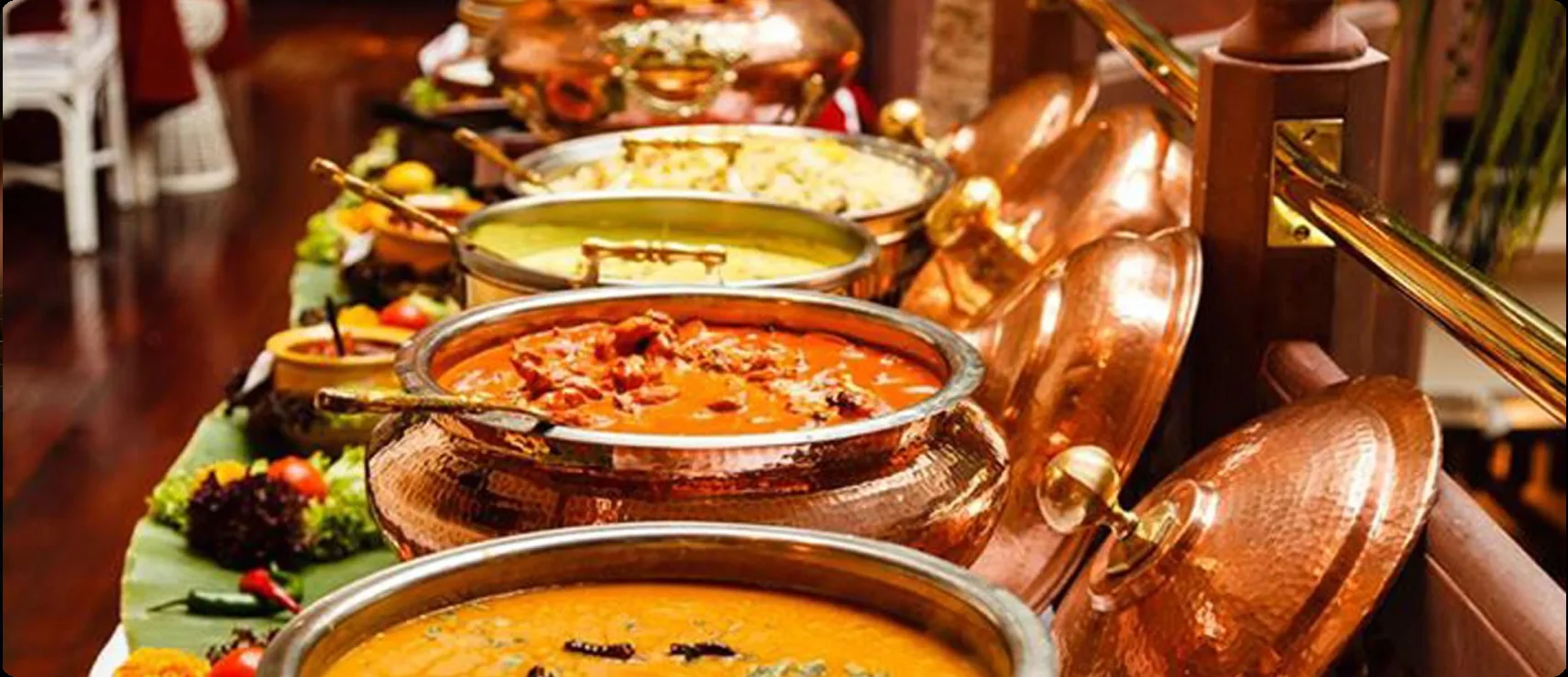 Buffet line of copper serving pots filled with Indian curries and dishes